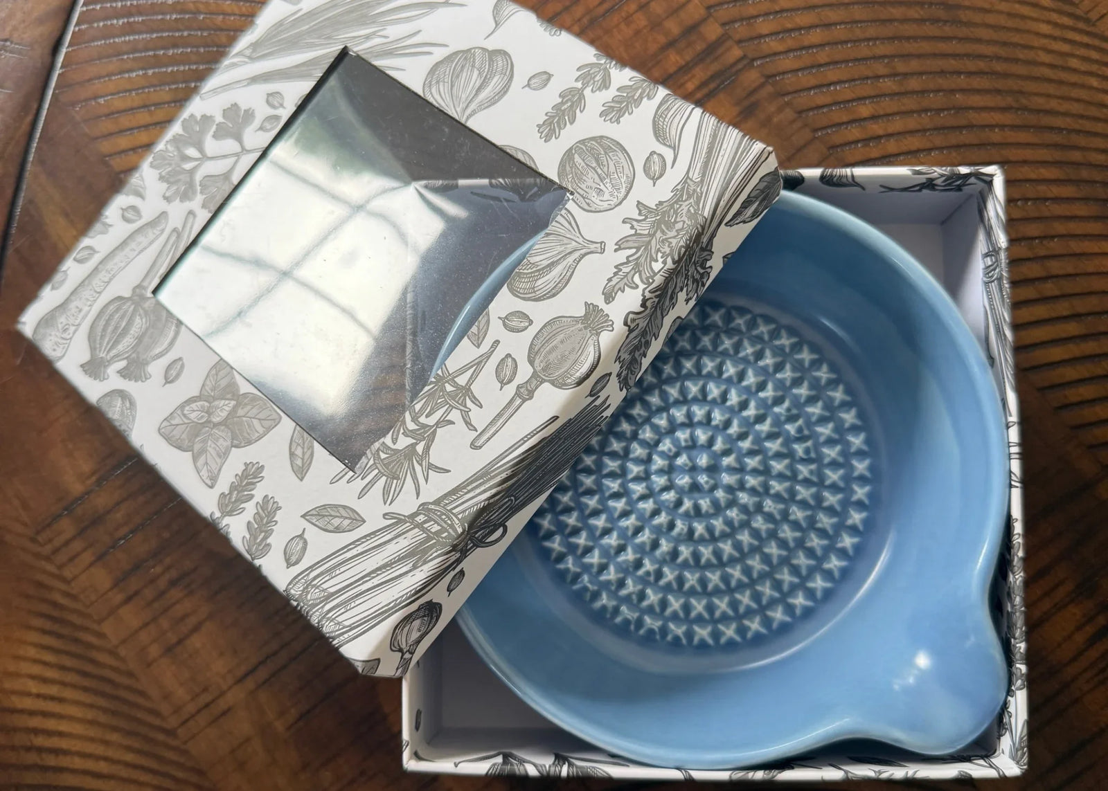 Blue garlic grater bowl with fresh herbs and garlic